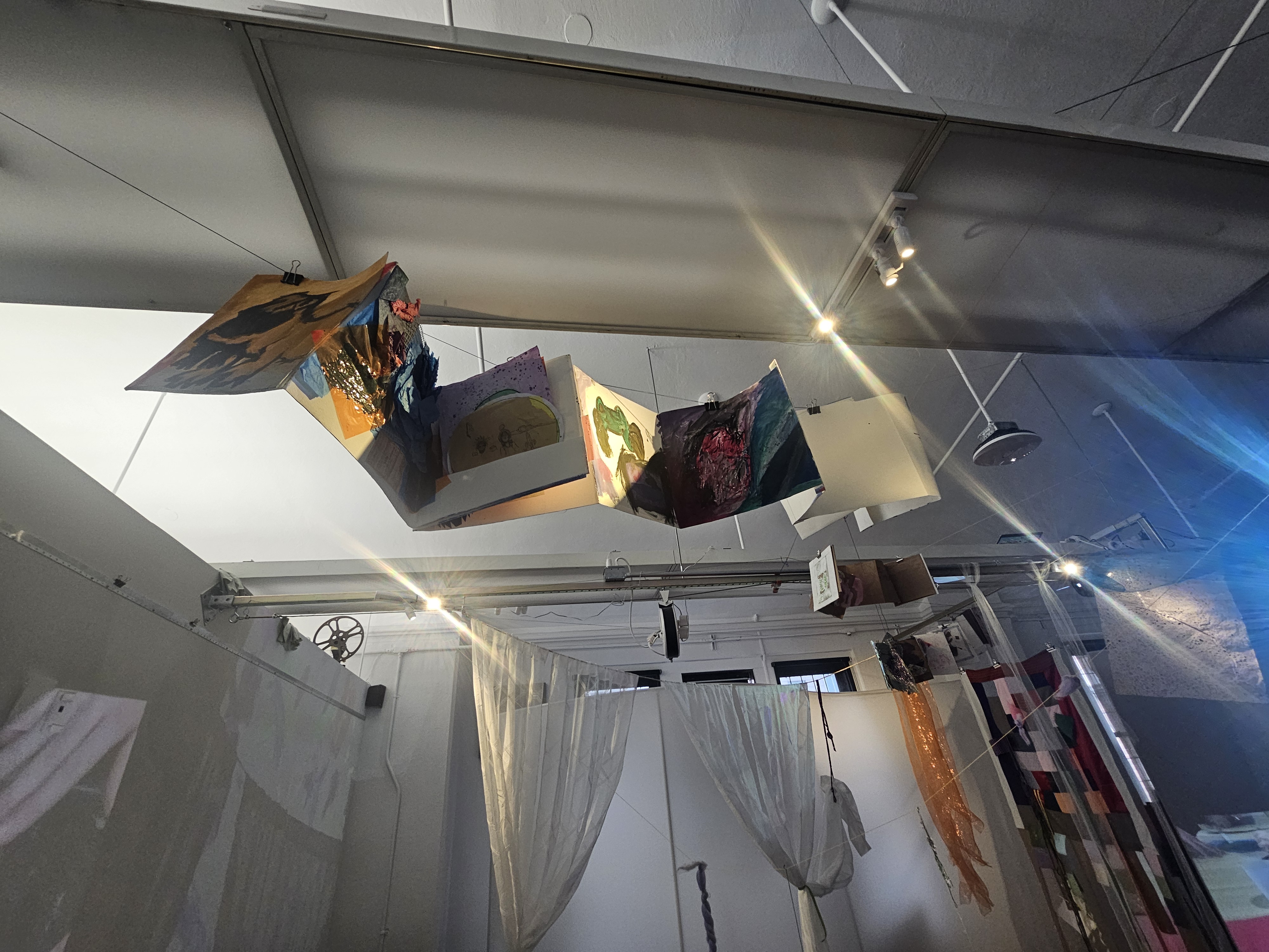 a photo of an unfolding accordion book created by a student, hanging from the ceiling, with light peeking through.